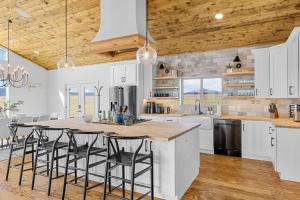 a kitchen with white cabinets and a large island with bar stools at Luxury Off-Grid Cabin with Stargazing Deck & Views in Fairplay +46 photos