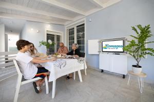 a group of people sitting at a table watching tv at Villetta with private jacuzzi in San Mauro a Mare
