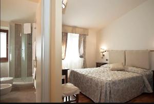 a bedroom with a bed and a bathroom with a tub at Hotel Arcobaleno in Siena