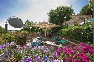a garden with tables and an umbrella and flowers at Hotel Arcobaleno in Siena