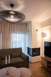 a living room with a couch and a television at KLA Luxury Boutique Villa with Pool & Jacuzzi by WESTBOOKING GR in Nikiana