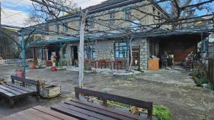 a building with two wooden benches in a courtyard at Βωλίτης Ξενώνας - Παραδοσιακό Καφενείο Ζαγορίου in Papingo
