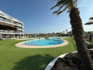 a swimming pool with a palm tree and a building at CJ186 - Ciudad Jardin I, Prime - ServHouse in El Borseral