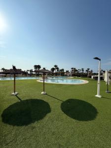 a golforie with umbrellas on the grass with a pool at CJ186 - Ciudad Jardin I, Prime - ServHouse in El Borseral