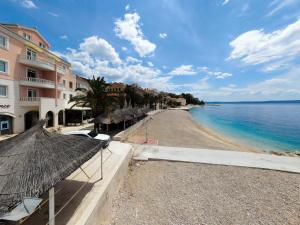 a beach with umbrellas and buildings and the ocean at Villa Sunce Beachfront in Podgora