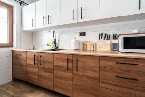 a kitchen with wooden cabinets and a microwave at Tarasówka u Zająca in Zakopane