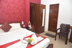 ein Hotelzimmer mit einem Bett, einem Stuhl und Blumen in der Unterkunft RD HOTEL-Bhavani Road in Erode