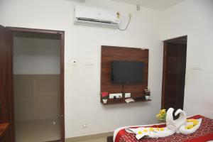 ein Zimmer mit einem Fernseher und einem Bett mit einem Schwan darauf in der Unterkunft RD HOTEL-Bhavani Road in Erode