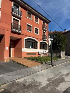 a red brick building with a wooden deck next to a street at La Terraza de Sovega in Arenas de Cabrales