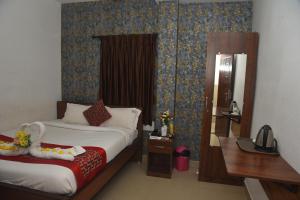 ein Schlafzimmer mit einem Bett, einem Schreibtisch und einem Spiegel in der Unterkunft RD HOTEL-Bhavani Road in Erode + 3 Fotos