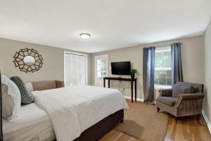 a bedroom with a bed and a chair and a television at Oglethorpe Manor Garden Level in Savannah