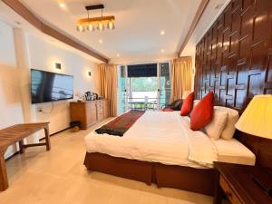 a bedroom with a large bed and a television at Rainbow Arokaya Welness Resort in Ban Hua Sai