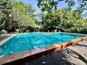 a swimming pool in a resort with trees in the background at Rainbow Arokaya Welness Resort in Ban Hua Sai