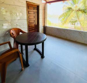 a table and a chair in a room with a window at Suits by lowtide in Udupi
