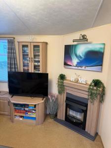 a living room with a flat screen tv and a fireplace at The West Lakes Caravan in Lamplugh