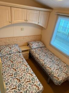 a bedroom with two beds and a window at The West Lakes Caravan in Lamplugh