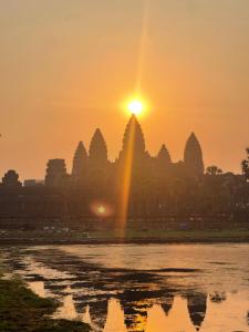 a sunset with the sun setting over a temple at Angkor Nature Voyages in Phumi Ta Phul