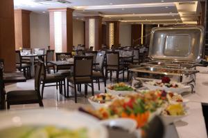 a dining room with tables and chairs and plates of food at Coral Hotel Karbala in Karbala