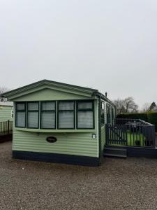 a green tiny house sitting in a parking lot at The West Lakes Caravan in Lamplugh +21 photos