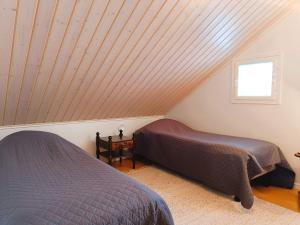 two beds in a room with a sloped ceiling at Villa Ilves A in Syöte