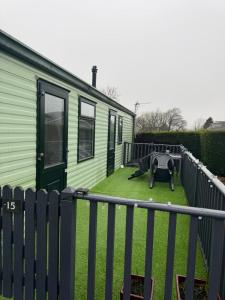 a green house with a yard with a fence at The West Lakes Caravan in Lamplugh