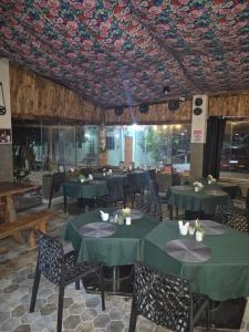 a dining room with green tables and chairs and a floral ceiling at Pousada Casa Verde in Cordisburgo