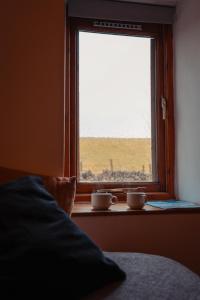 two cups sitting on a window sill next to a bed at The Royal Oak in Buxton
