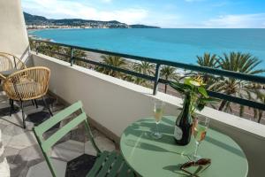 a table with wine glasses and a vase with flowers on a balcony at Baie des Anges in Nice