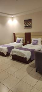 a hotel room with two beds and a couch at عمارة النفيسة شقة 18 in Unayzah