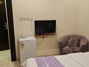 a room with a tv and a chair and a bed at عمارة النفيسة شقة 18 in Unayzah