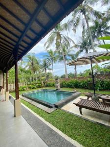 a swimming pool with a bench and an umbrella at Shima Tunjung in Darmasaba +6 photos