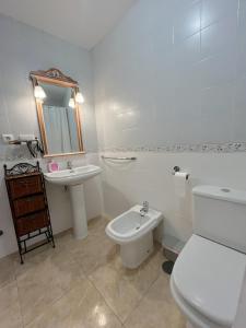 a white bathroom with a toilet and a sink at The Llanete Collection 01 in Martos