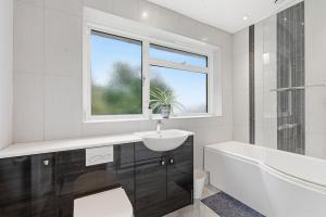 a white bathroom with a sink and a tub and a window at Luxury 5 Bedroom with Pool & Games Room in Potter Street +16 photos