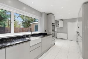 a kitchen with white cabinets and a large window at Luxury 5 Bedroom with Pool & Games Room in Potter Street