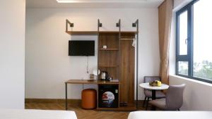 a living room with a table and a tv in a room at Hilaria Hotel in Vạn Ninh