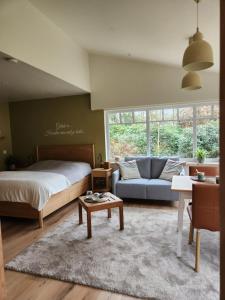 a bedroom with a bed and a couch and a table at B&B 't Greefsch Geluck in Kalmthout +50 photos
