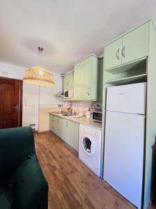 a kitchen with green cabinets and a white refrigerator at The Llanete Collection 02 in Martos +6 photos
