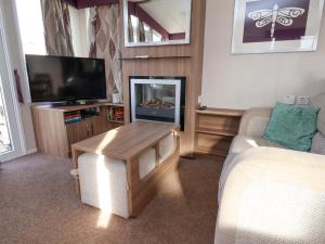 a living room with a couch and a tv at Caravan B14 Beechrise in Filey