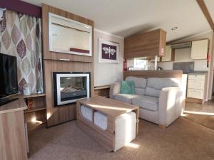 a living room with a couch and a television at Caravan B14 Beechrise in Filey
