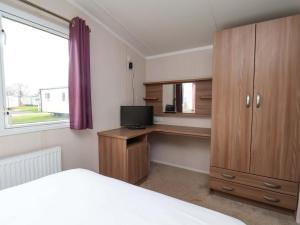 a bedroom with a bed and a desk with a television at Caravan B14 Beechrise in Filey