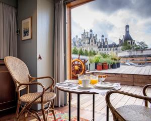 a table and chairs in a balcony with a view of a city at Relais de Chambord, a Small Luxury Hotels of the World in Chambord