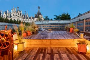 a wooden deck with potted plants on top of a building at Relais de Chambord, a Small Luxury Hotels of the World in Chambord