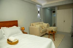 a bedroom with a bed and a couch and a chair at Nyumbani 2 studio in Dar es Salaam