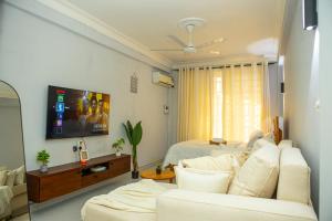 a living room with a white couch and a tv at Nyumbani 2 studio in Dar es Salaam