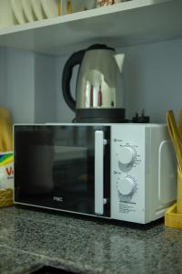 a microwave on a counter with a coffee pot on top at Nyumbani 2 studio in Dar es Salaam