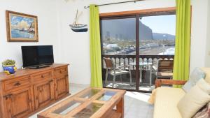 a living room with a television and a balcony at La Playa 2 B in La Laja