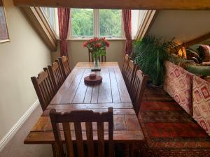a wooden table with chairs and a vase of flowers on it at Moorgarth Hall Apartment, Ingleton, Yorkshire Dales in Ingleton