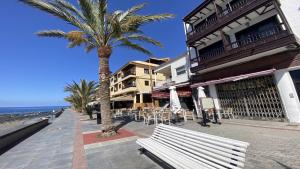 a bench in front of a building with a palm tree at La Playa 2 A in La Laja