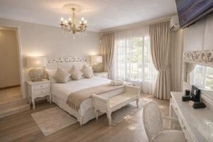 a bedroom with a large bed and a chandelier at La Barune Guest House in Tzaneen +28 photos
