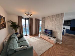ein Wohnzimmer mit einer grünen Couch und einem Fernseher in der Unterkunft Panoramic Blue in TÄƒuÅ£ii MÄƒgheruÅŸ